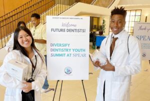 Two happy future dentists standing in front of a Diversify Dentistry sign